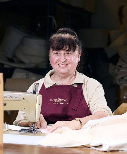 Royal Pedic employee sewing fabric on a sewing machine in a workshop