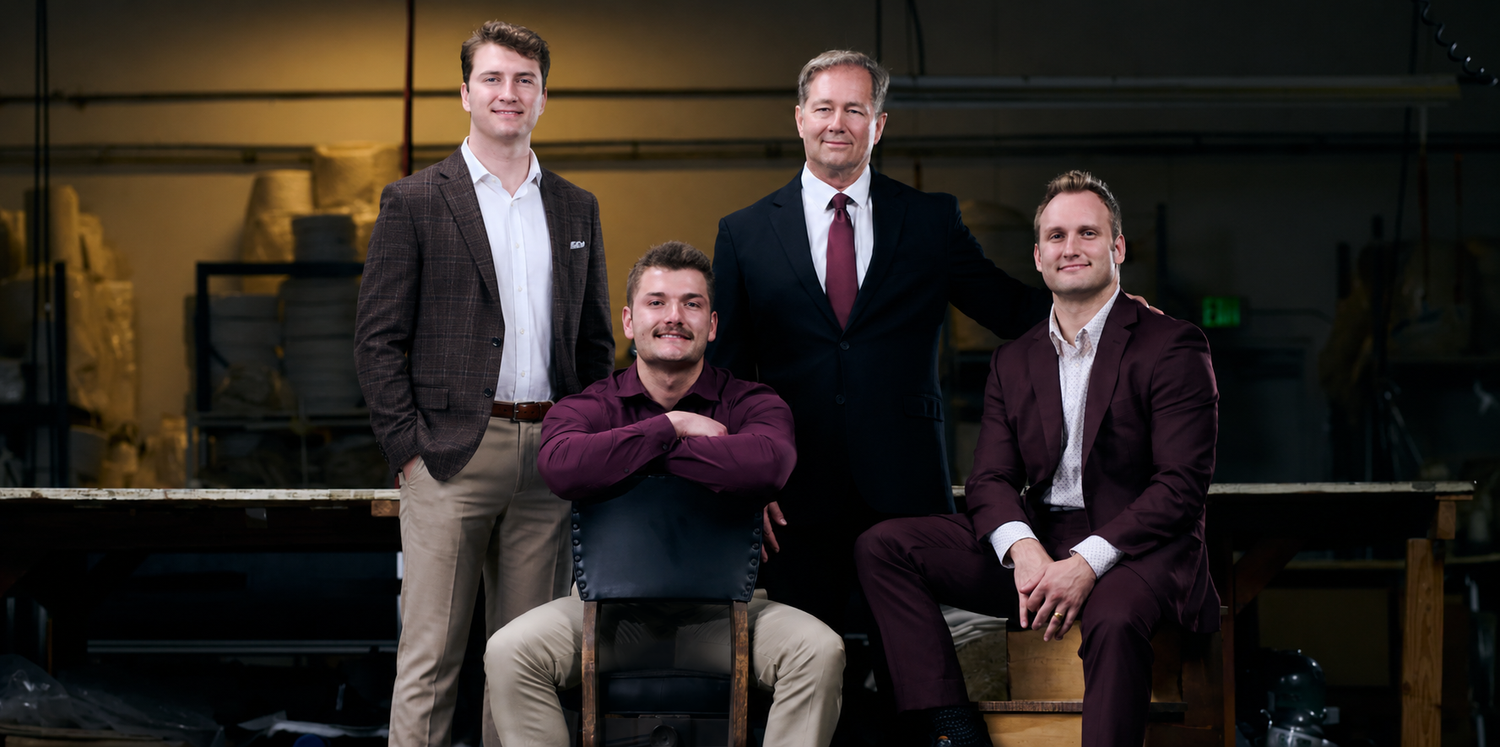 Four men in business attire posing in a warehouse setting