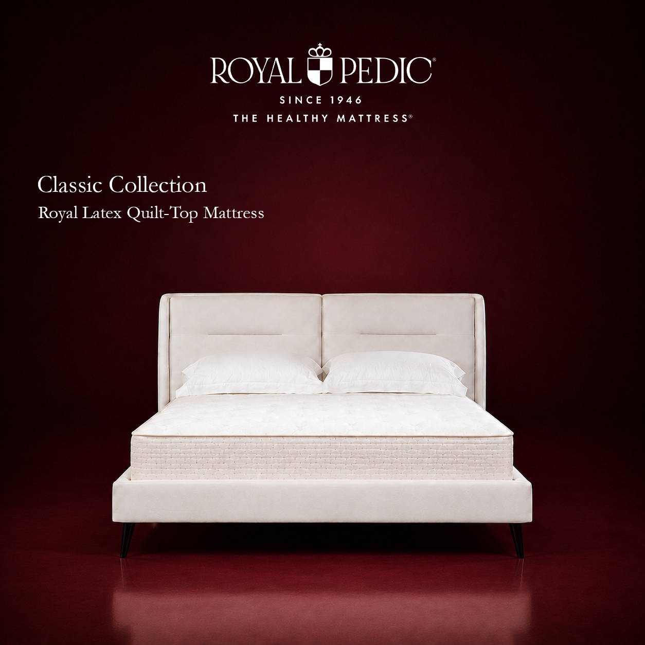 Royal Pedic Royal Latex Quilt-Top Mattress on a white upholstered bed frame against a dark red background