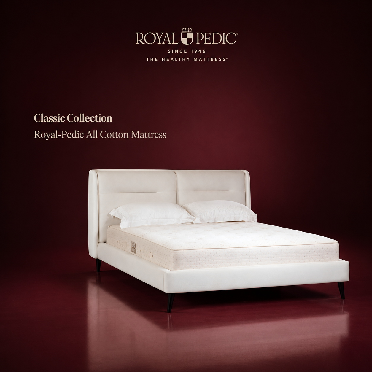 Royal-Pedic All Cotton Mattress from the Classic Collection on a white upholstered bed frame against a dark red background