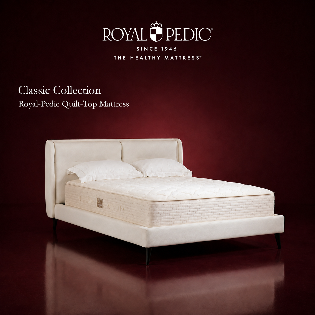 Royal-Pedic Quilt Top Mattress from the Classic Collection on a cream upholstered bed frame against a dark red background