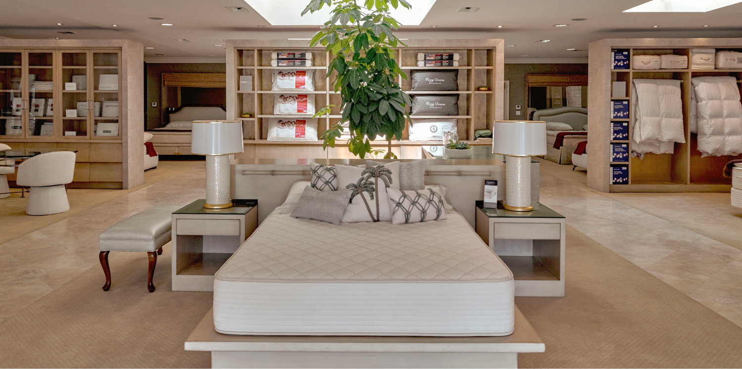 Bedroom furniture display with bed, nightstands, and lamps in a Royal-Pedic showroom setting.