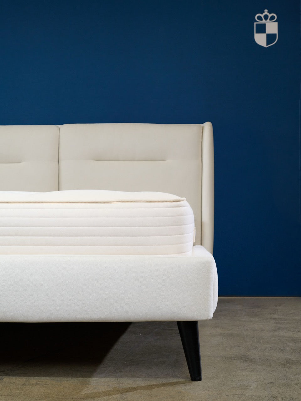 Royal-Pedic Natural Cotton w/ Wool Wrap Mattress on a white bed frame against a blue wall.