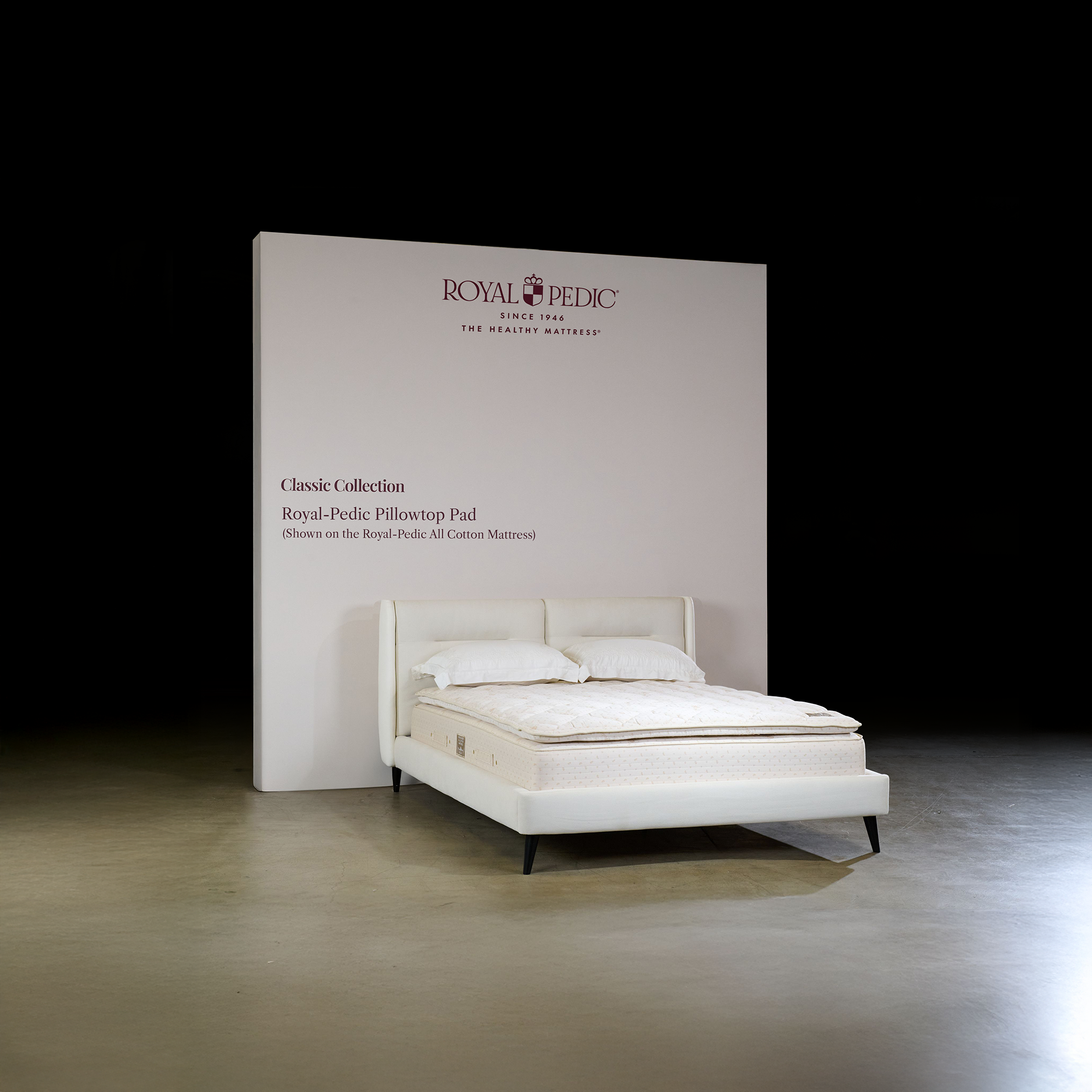 White bed with a white mattress and pillowtop pad on a dark background, featuring Royal Pedic branding.