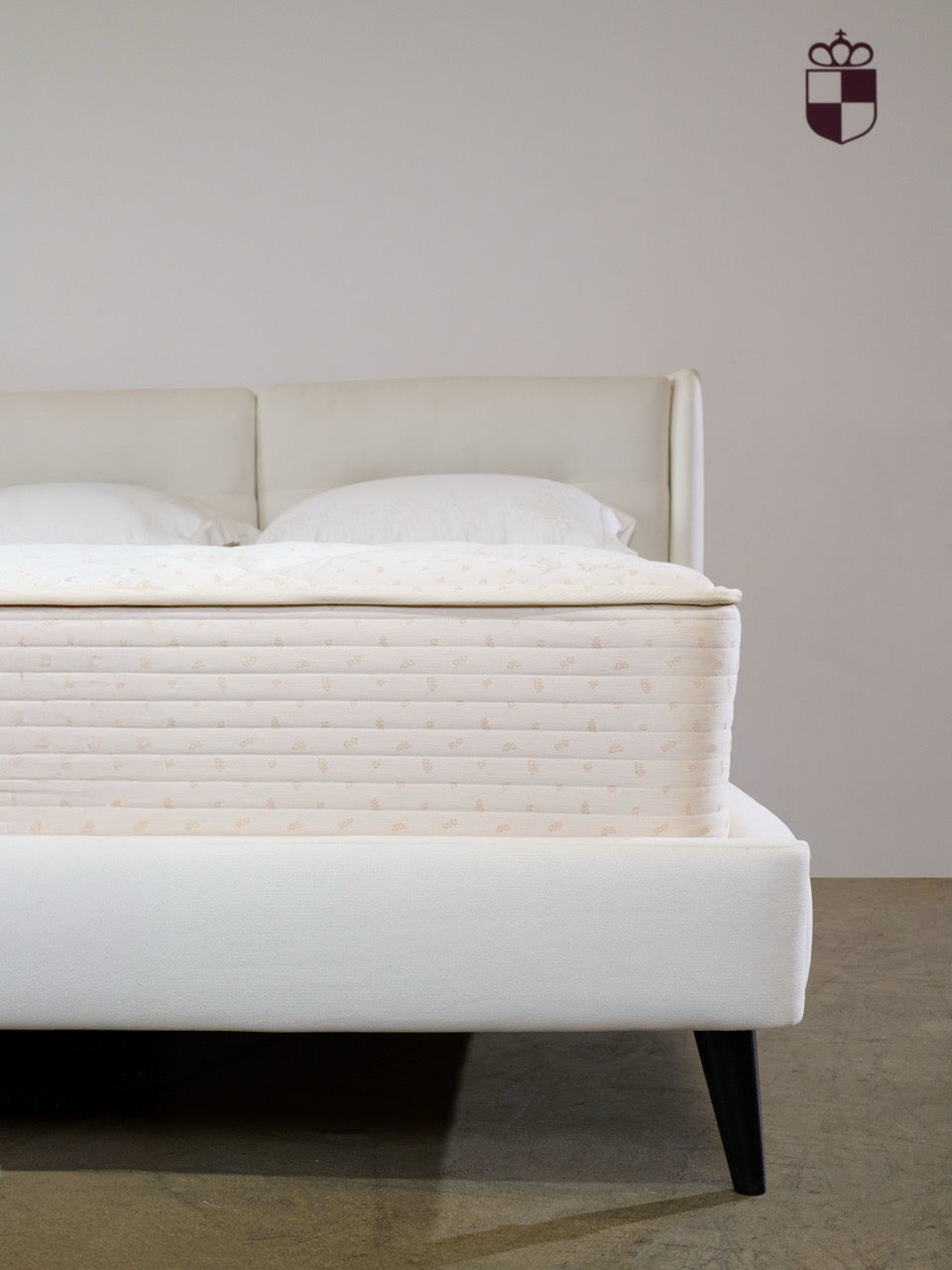 Royalpedic Royal Latex Quilt-Top Mattress on a white bed frame with pillows and a headboard. The Royalpedic logo is on the wall.