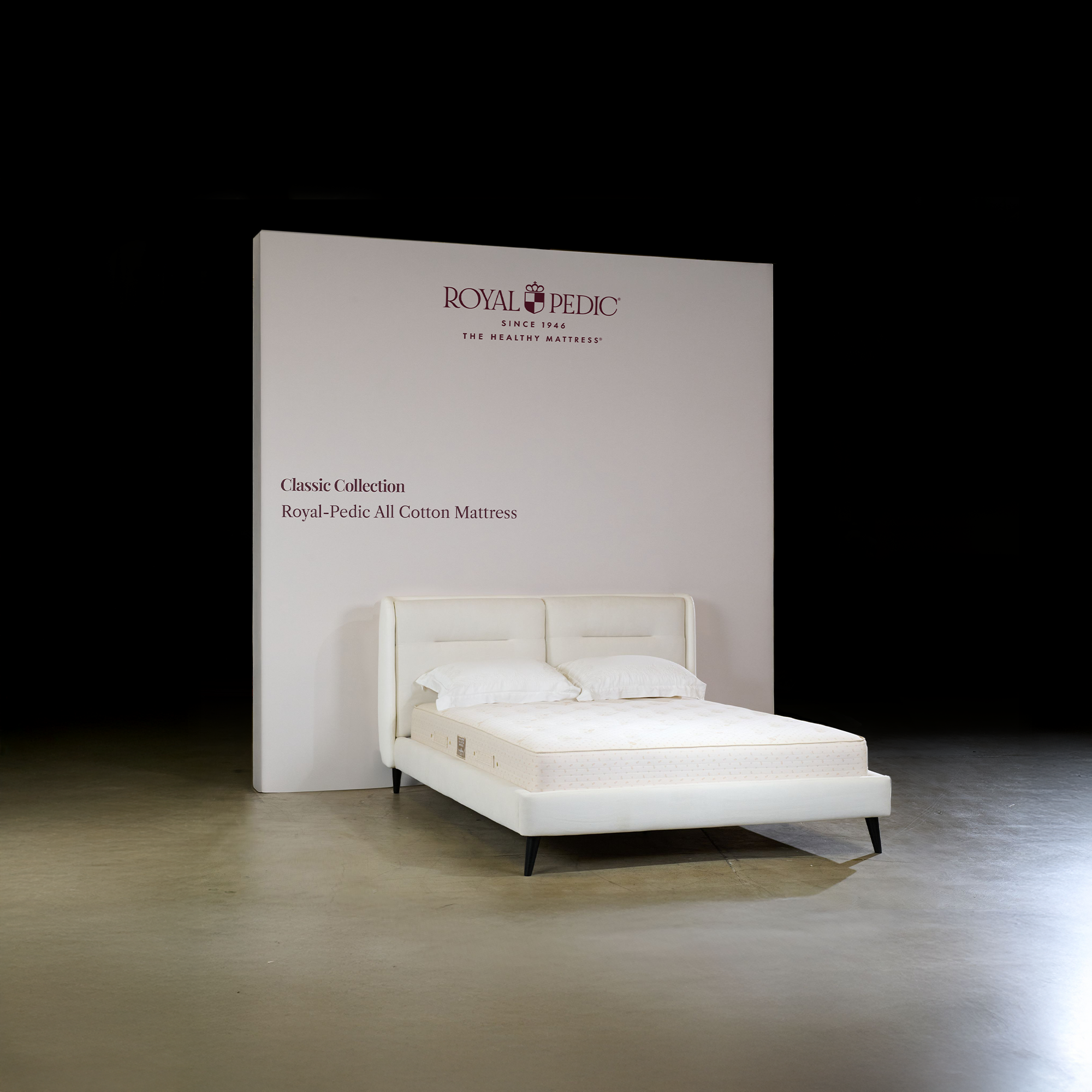 White mattress on a bed frame with a 'Royal Pedic' branded backdrop.