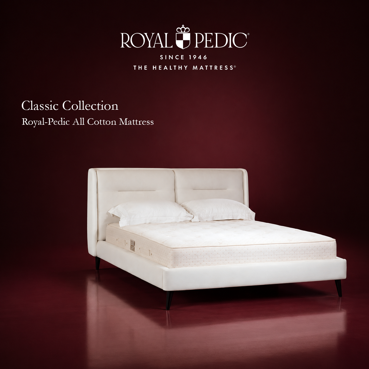 Royal-Pedic All Cotton Mattress from the Classic Collection on a white upholstered bed frame against a dark red background