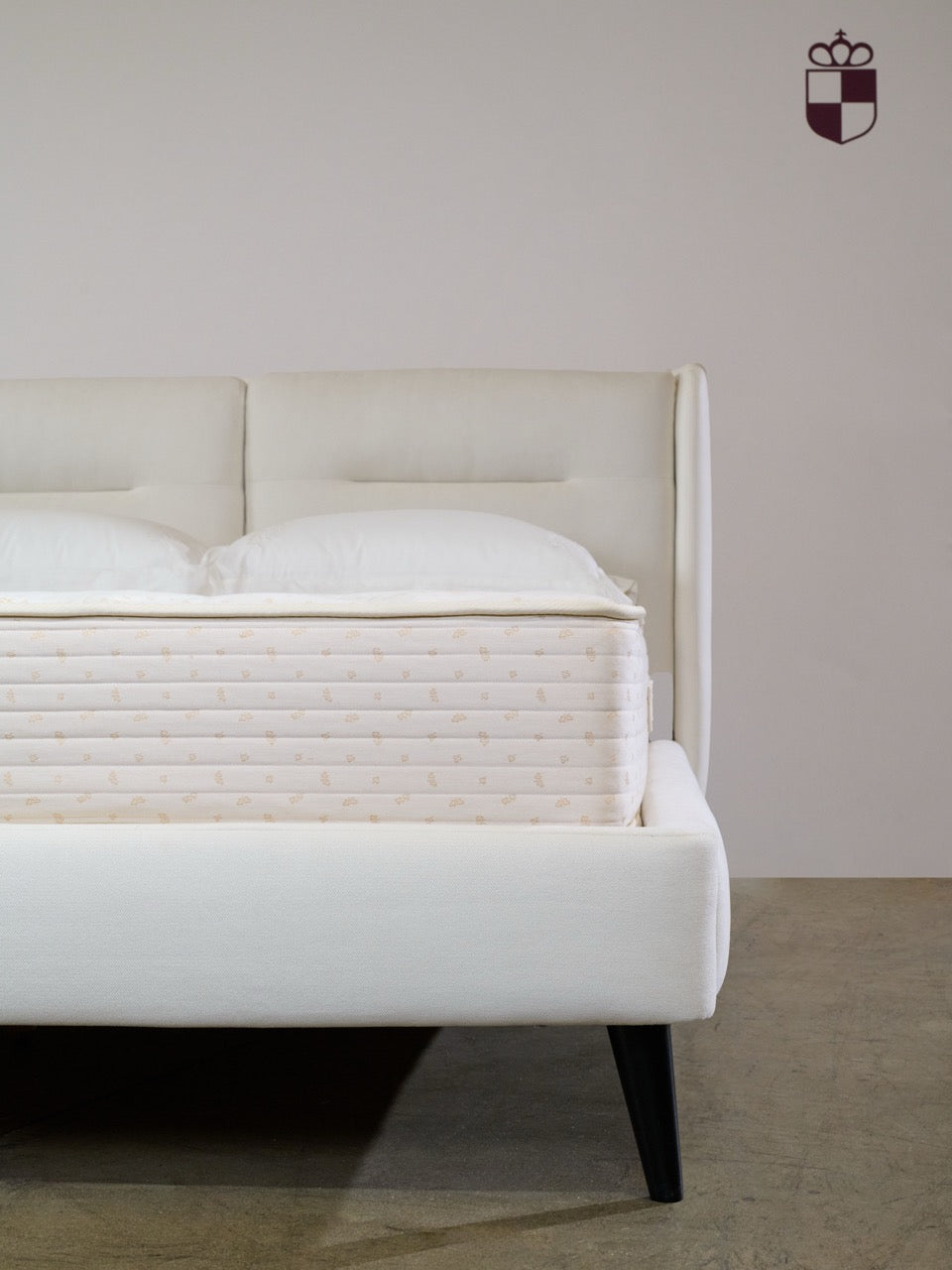 Royal-Pedic Quilt Top Mattress on a white bed frame with a Royal-Pedic logo on the wall.